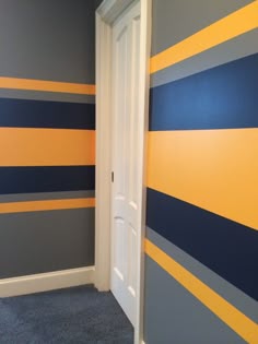 an empty room with blue, yellow and gray stripes on the wall next to a white door