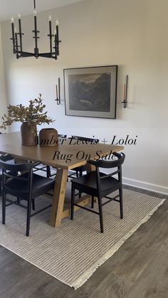 a dining room table with black chairs and a rug on the floor in front of it