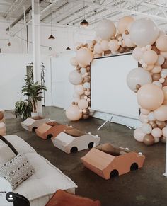 balloons are hanging from the ceiling in an industrial space with couches and pillows on the floor