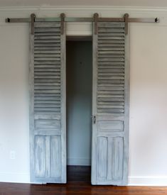 an open door with wooden slats on the inside and outside, in front of a white wall