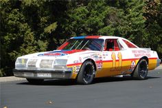 an old race car with numbers painted on it's side driving down the road