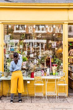 a woman sitting at a table in front of a flower shop