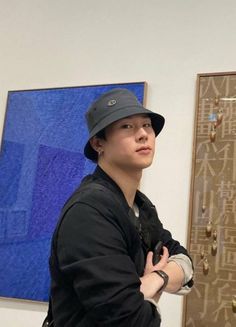 a young man standing in front of a blue and brown wall with jewelry hanging on it