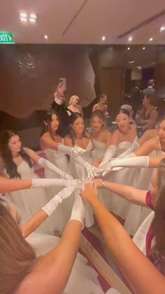 a group of women in white dresses holding hands together