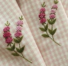 pink flowers are embroidered onto the side of a white checkered fabric with green leaves