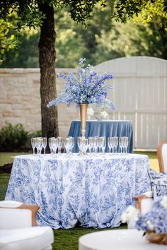 the table is set with wine glasses and vases on it for an outdoor function