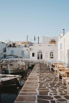 tables and chairs are lined up along the water's edge in front of white buildings