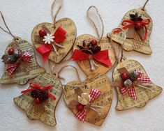 six wooden heart ornaments with red bows and pine cones on sheet music sheets, hanging from twine