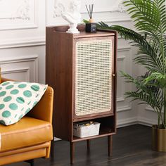 a brown cabinet sitting next to a chair in a living room with a potted plant