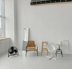 an empty room with three chairs and two stools in front of a large window