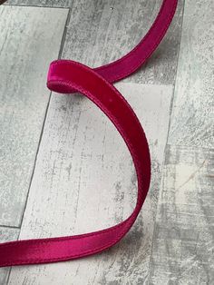 a pink ribbon laying on top of a wooden floor