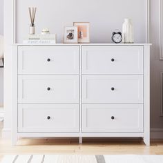 a white dresser with several drawers and pictures on top