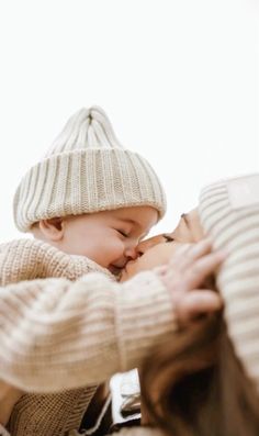 a woman holding a baby in her arms while wearing a knitted hat and sweater