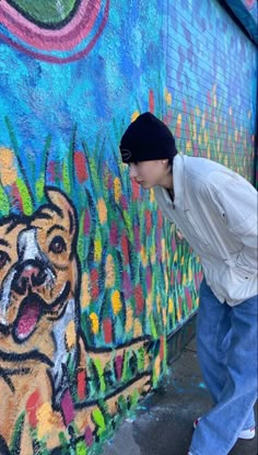 a young man standing in front of a wall with graffiti on it's side