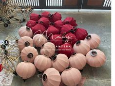 many pink and red paper lanterns are on the ground next to each other with black string