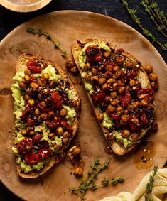 two pieces of bread topped with guacamole and beans on a wooden plate