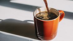 a cup of coffee being poured into it