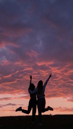 two people jumping in the air at sunset