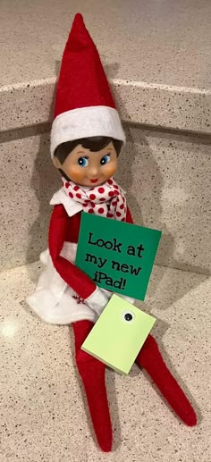 an elf holding a sign that says look at my new ipad