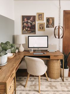 a desk with a computer on top of it next to a chair and potted plant