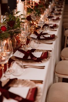 a long table is set with place settings and wine glasses, napkins, and candles