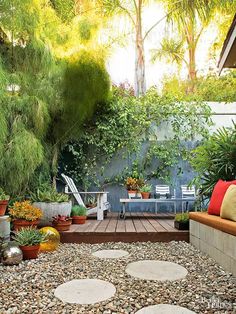 an outdoor area with rocks and plants on the ground, in front of a wooden deck