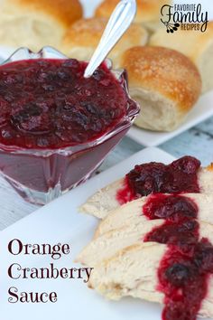 an orange cranberry sauce is in a glass bowl next to bread on a plate