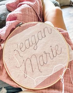 a woman is holding a hand embroidered sign