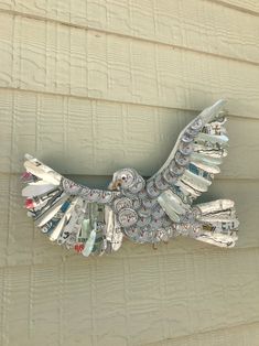 an eagle made out of magazines sitting on the side of a building with it's wings spread