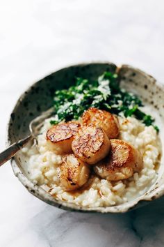 a bowl filled with rice and seared scallops on top of a table