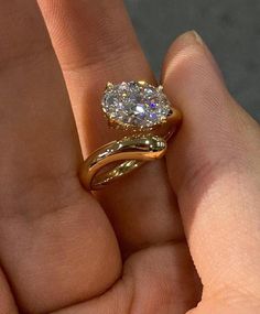 a woman's hand holding an engagement ring with a diamond in the middle and a gold band around it