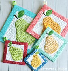 four quilted coasters with apples and pears on them