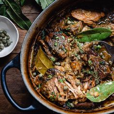 a pot filled with meat and vegetables on top of a wooden table