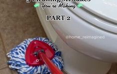 a red mop sitting on top of a bathroom floor next to a white toilet