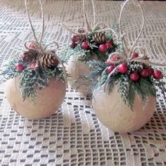 three white vases with red berries and pine cones