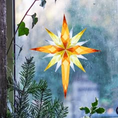 an origami star hanging on a window sill next to a tree branch