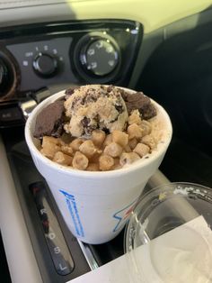 an ice cream sundae with chocolate chips in a cup on the car dash board