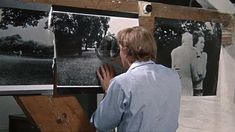 a man is looking at pictures hanging on the wall