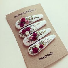 three white hair clips with red and pink flowers on them