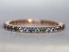 a close up view of a wedding band with blue and green stones on the side