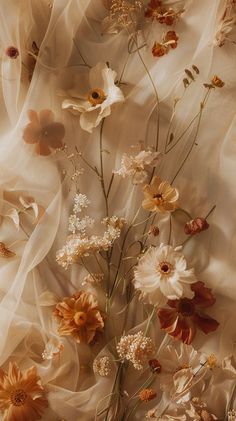 a bunch of flowers that are sitting on a table cloth with sheer fabric behind them