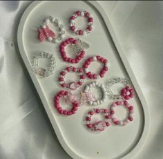 a white tray with pink and white bracelets on it's side, sitting on a white sheet