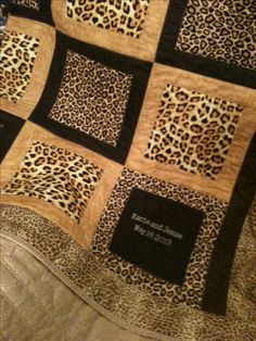 an animal print quilt on top of a bed next to a blanket with the name and date printed on it