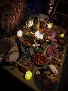 a table topped with lots of food next to candles and plates filled with meats