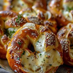 several pretzels covered in cheese and herbs on a platter with other pretzels