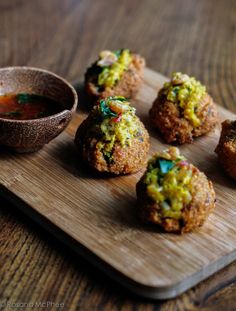 some food is sitting on a cutting board next to a small bowl and dipping sauce