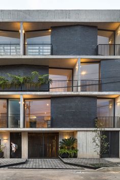 an apartment building with balconies and plants on the balconies are lit up at night