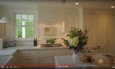 an image of a kitchen setting with flowers on the counter and candles in the vase