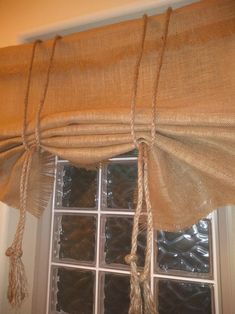 a window with some burlocks hanging from it's side and the curtains pulled back