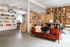 a dog sitting on top of a red couch in a room filled with bookshelves